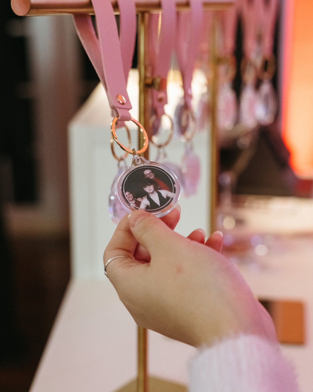 Hand holding a round clear photo charm of a couple on a blush strap with a gold ring